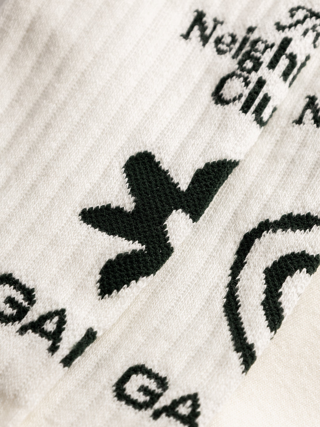 Close-up of GABbrise Socks - White by Gabba, crafted from ribbed cotton blend with black woven graphics, Gabba branding, abstract shapes, and partially visible 