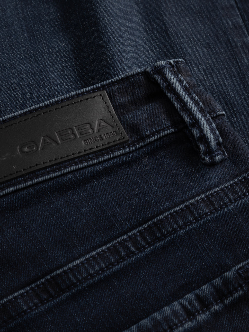 Close-up of GABjones Blueblack Jeans in blue black denim by Gabba, featuring a black leather brand patch with 