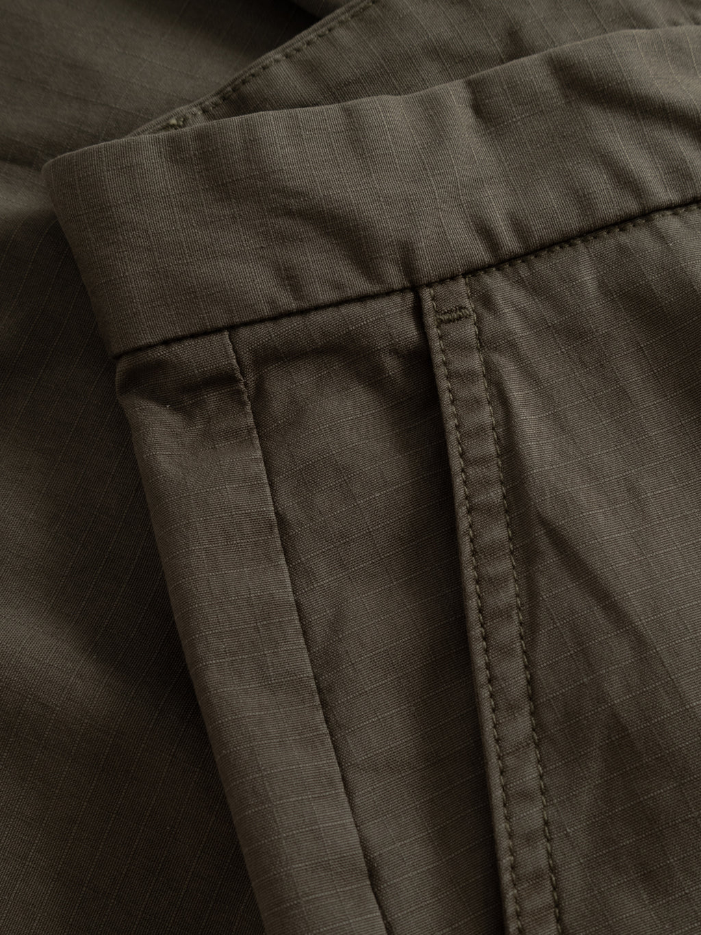 Close-up of GABjoli Cargo Ripstop Shorts - Army by Gabba shows the waistband, belt loop, and stitching with a subtle checkered texture, emphasizing the relaxed fit and versatile everyday style.