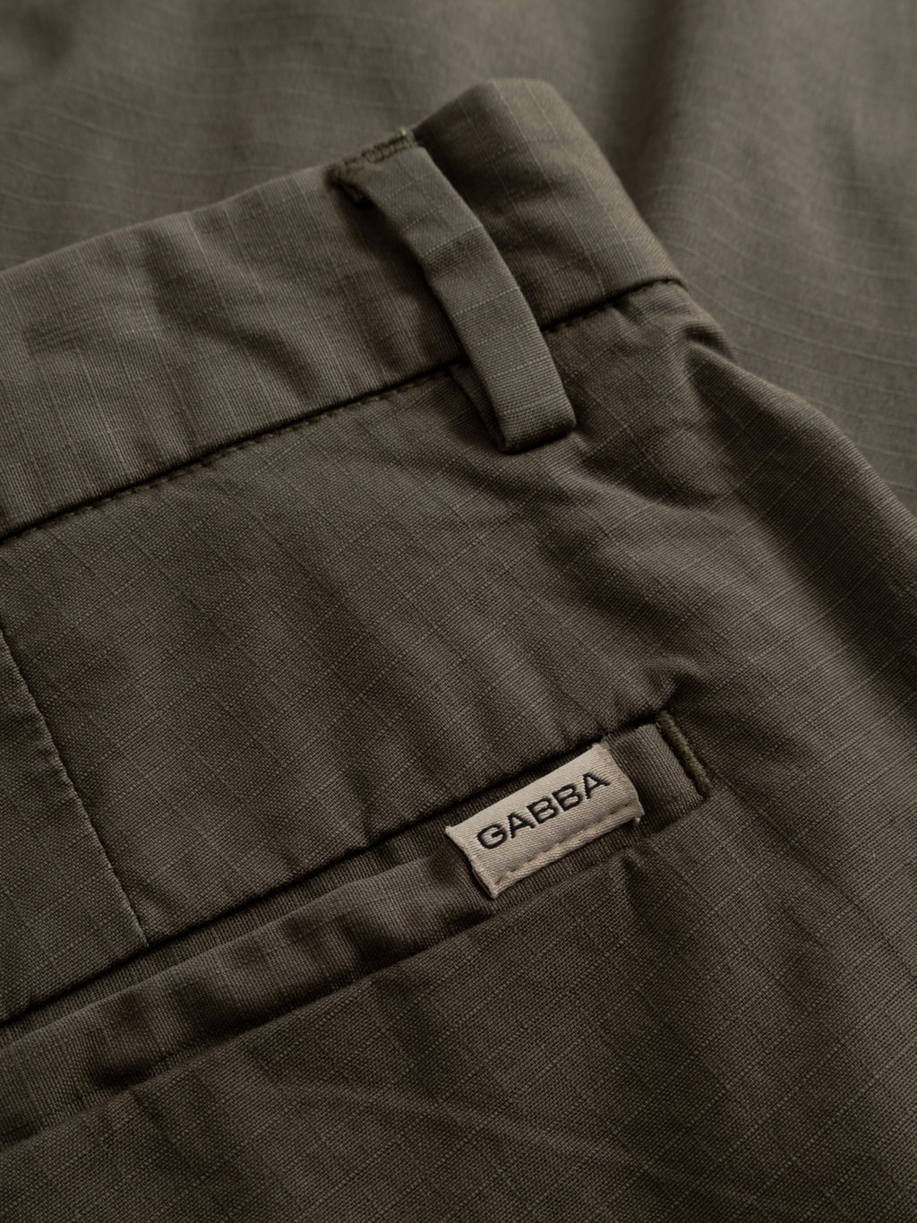 Close-up of Gabba GABjoli Cargo Ripstop Shorts - Army: relaxed-fit olive green shorts with belt loops, rear welt pocket with a small Gabba tag, side cargo pockets, and subtle grid texture for versatile everyday wear.