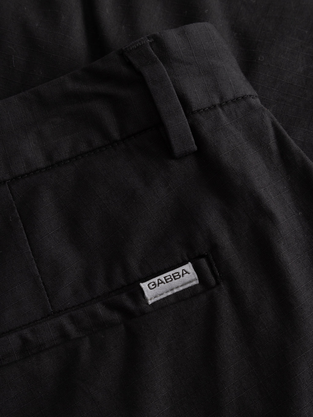 Close-up of GABjoli Cargo Ripstop Shorts in black by Gabba, showing a small fabric label above the back pocket, visible stitching, and belt loop—ideal for versatile everyday wear.