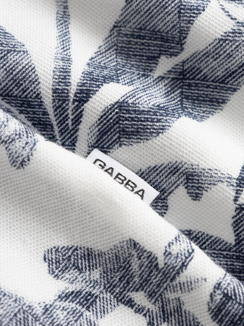 Close-up of the Gabba GABsven Reg Leaves SS Shirt - Flower Mix, a regular-fit piqué jersey cotton shirt with white fabric decorated with blue leaf patterns and a small white 