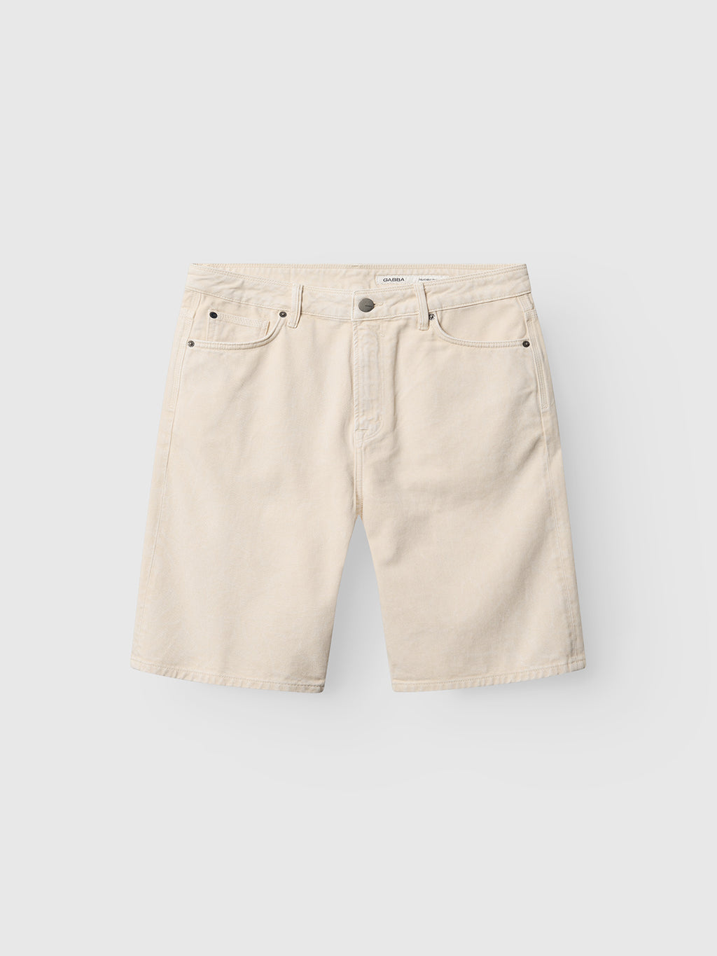 Gabba’s GABmox Antiq Shorts in Ecru are relaxed-fit, made from rigid twill, and feature front and back pockets, metal rivets, belt loops, and a buttoned waistband—shown flat on a light gray background.