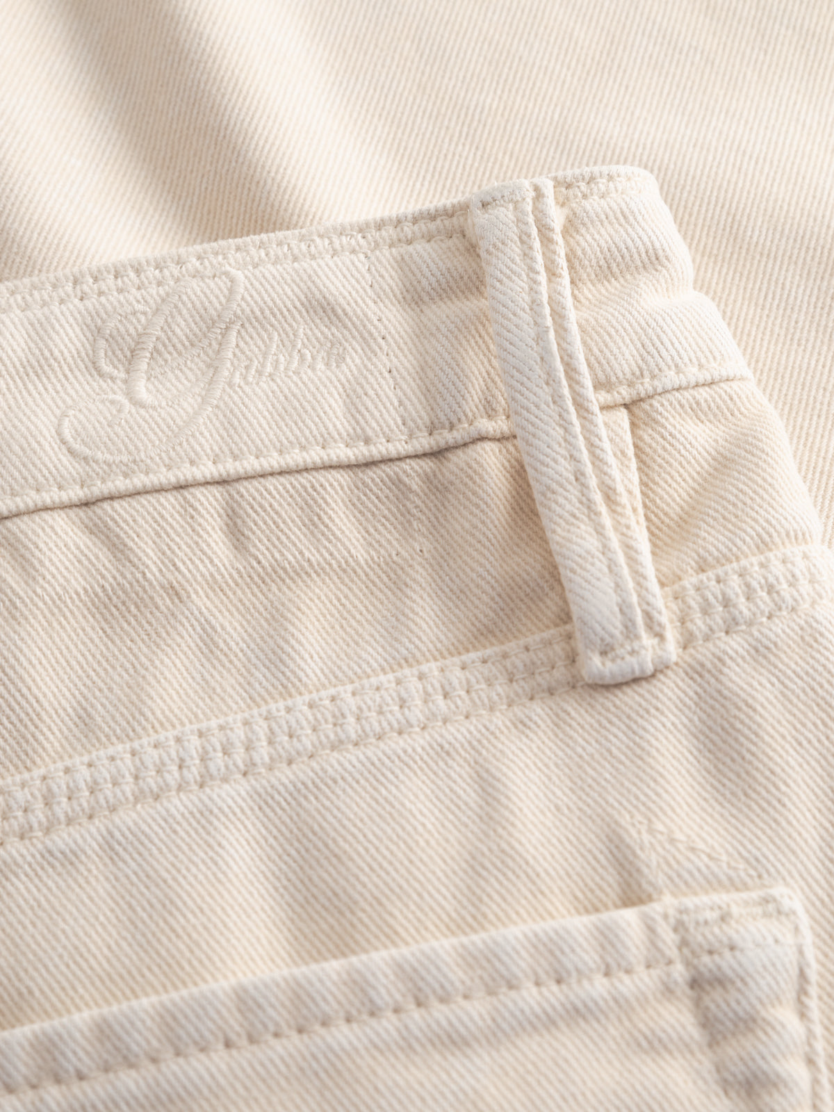 Close-up of Gabba GABmox Antiq Shorts in ecru, featuring rigid twill, belt loops, waistband, pocket stitching, and an embroidered Gabi logo. The garment-dyed antique finish and texture stand out.