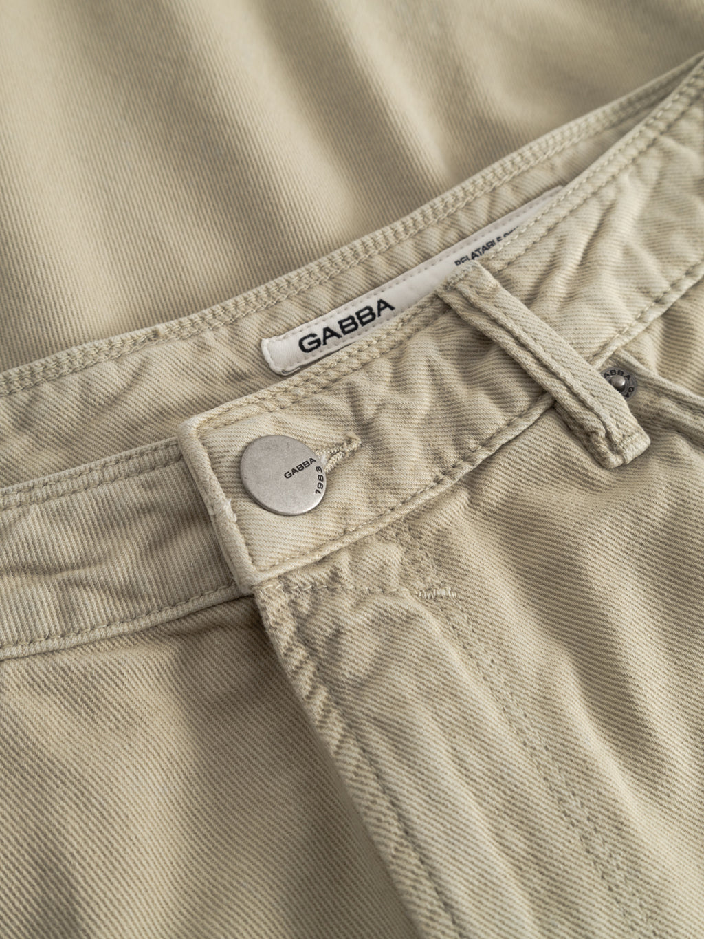 Close-up of GABmox Antiq Shorts in Alfa Green by Gabba, made from rigid twill denim with a visible metal button, belt loop, and a white Gabba label on the waistband.