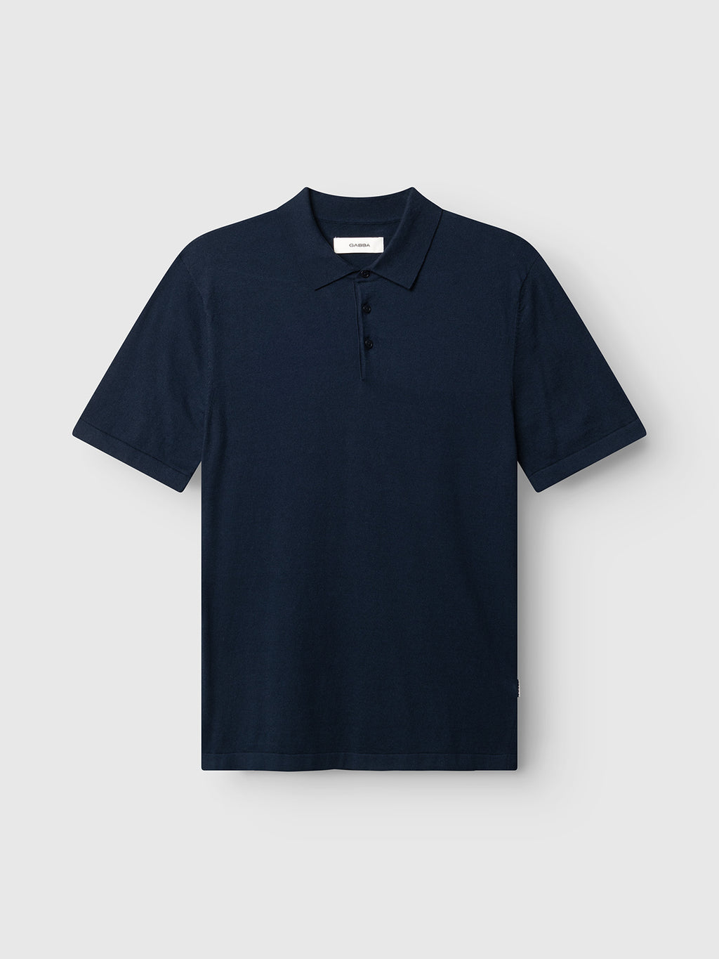 The Gabba GABbenson New Cot SS Knit - Navy Mel is a navy short-sleeve polo with a flat knit collar and three buttons, shown on a plain light gray background.