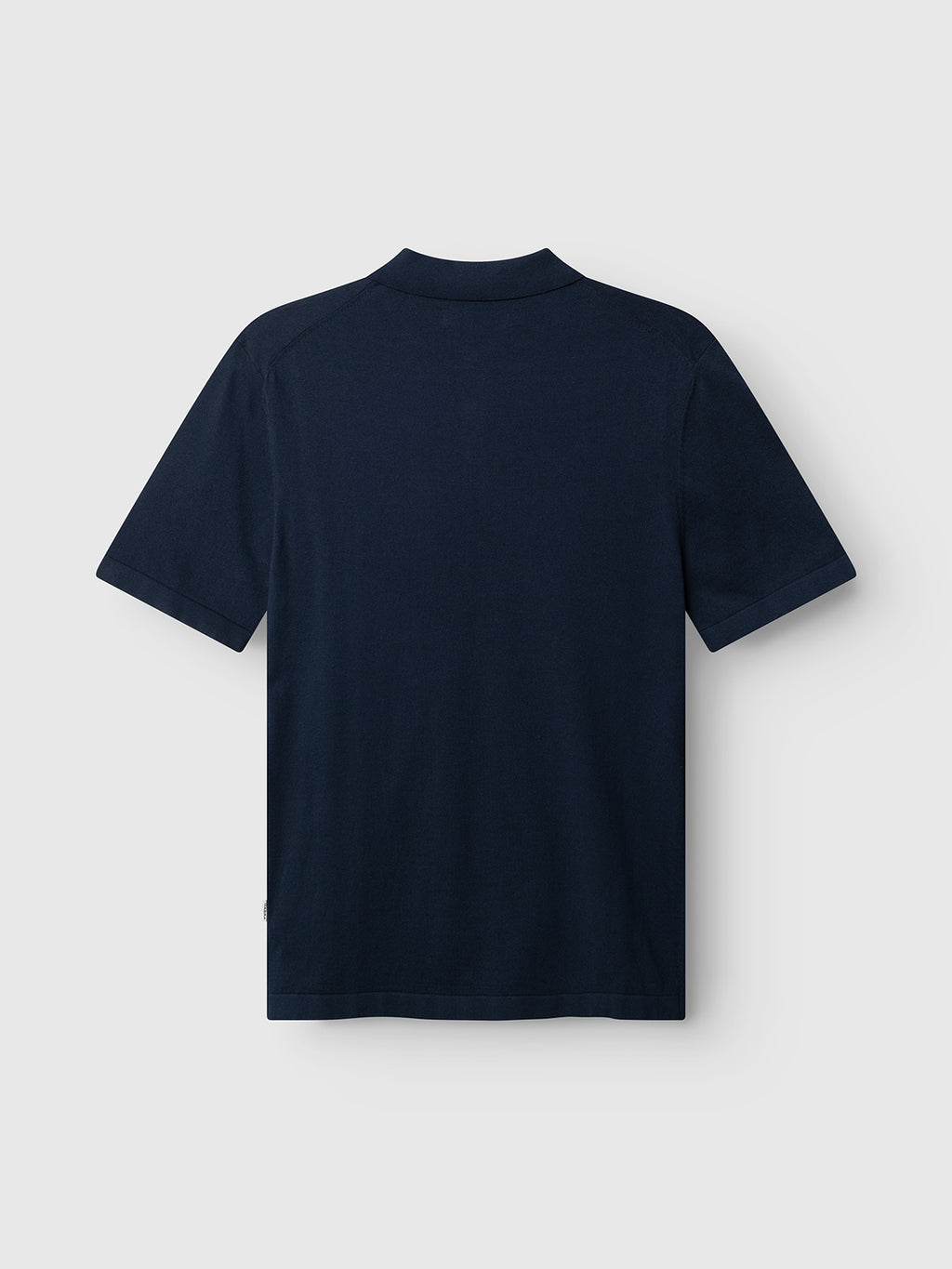 The Gabba GABbenson New Cot SS Knit - Navy Mel. polo is displayed laid flat, back side up, on a light gray background. The shirt features a classic plain, flat knit design in navy blue.