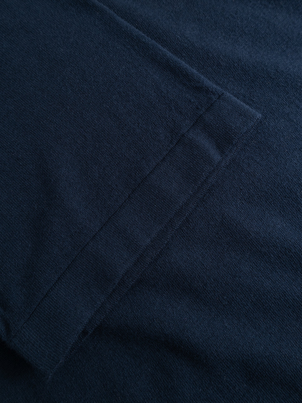 Close-up of the Gabba GABbenson New Cot SS Knit in Navy Mel, highlighting its flat knit texture, neatly stitched seam, and precise corner detail. The fabric is ideal for stylish short-sleeve polos or sweatshirts.