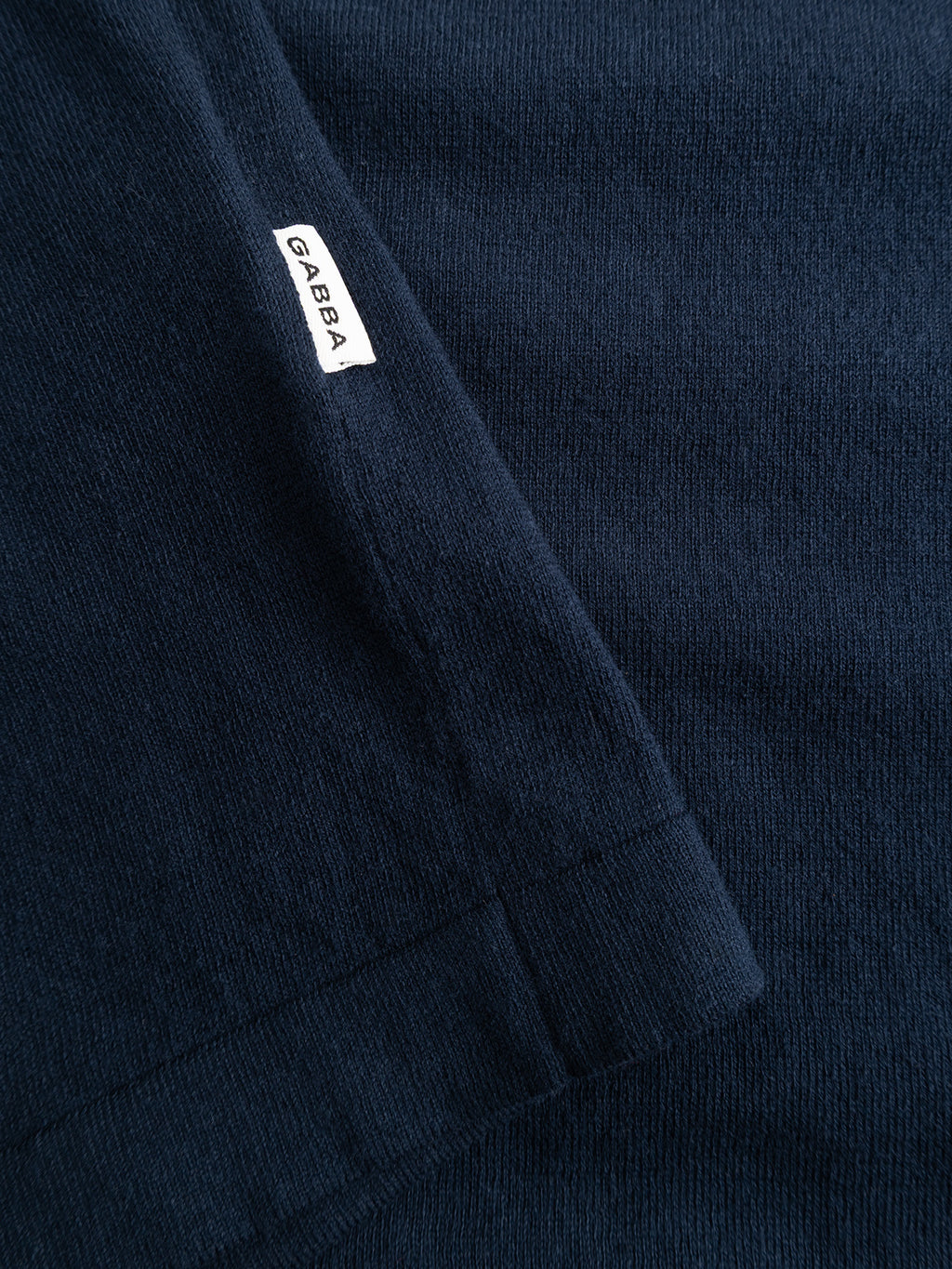 Close-up of the GABbenson New Cot SS Knit - Navy Mel. polo by Gabba, featuring dark blue ribbed fabric and a small white seam tag with the brand name in black.