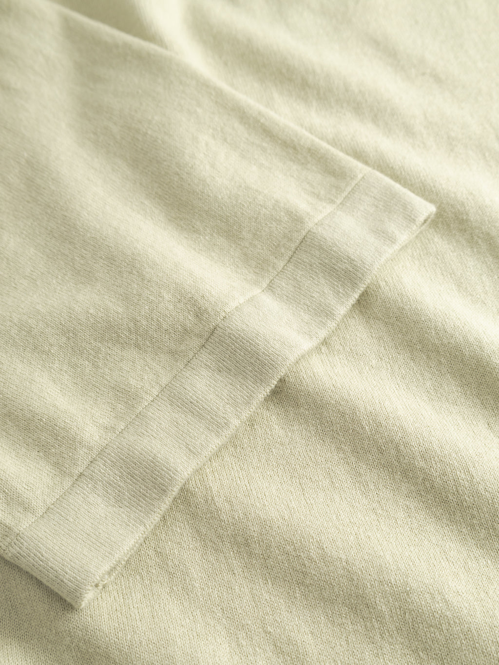 Close-up of the GABbenson New Cot SS Knit - Alfa Green by Gabba, highlighting the fabric texture and stitching detail near the sleeve hem of this men's polo shirt.