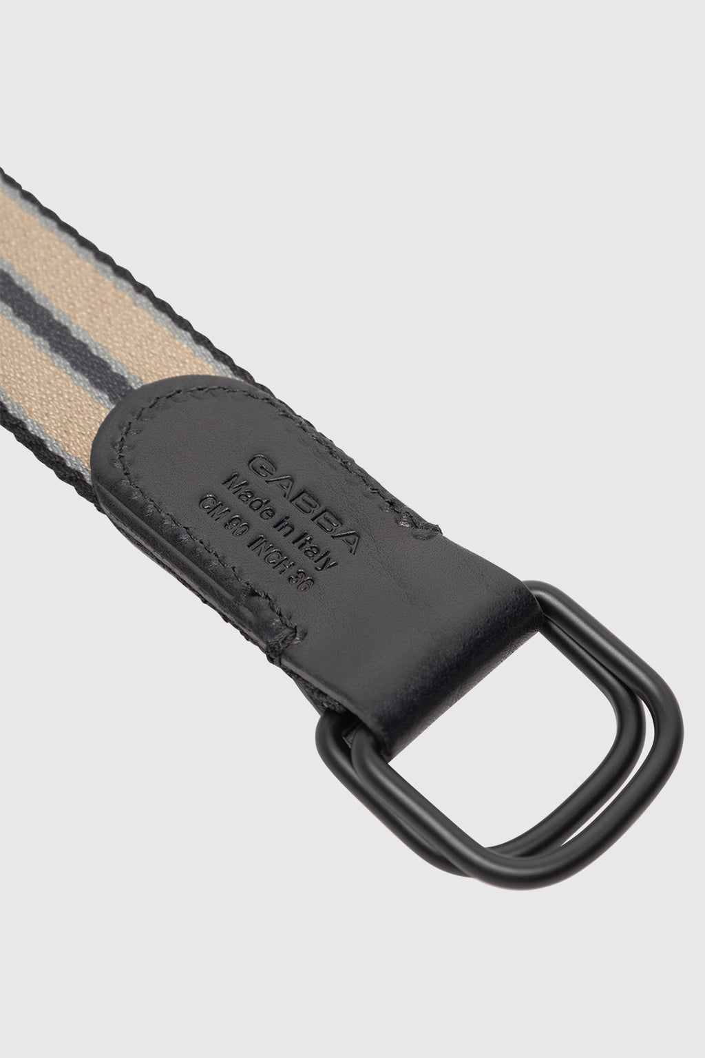Close-up of the GABstromboli Belt - Multi Stripe by Gabba, featuring beige and black striped fabric, black leather accents embossed with 'GAËBA, Made in Italy, 01R K10356', and a sleek black metal rectangular ring.