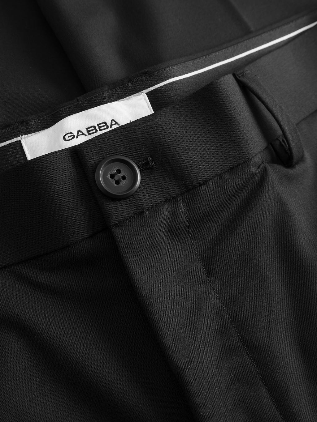 Close-up of Gabba GABjoe Tailor Dressy Pant in black, featuring a tapered fit, button closure, and visible belt loop. The white inner waistband tag shows the brand name Gabba in black letters.