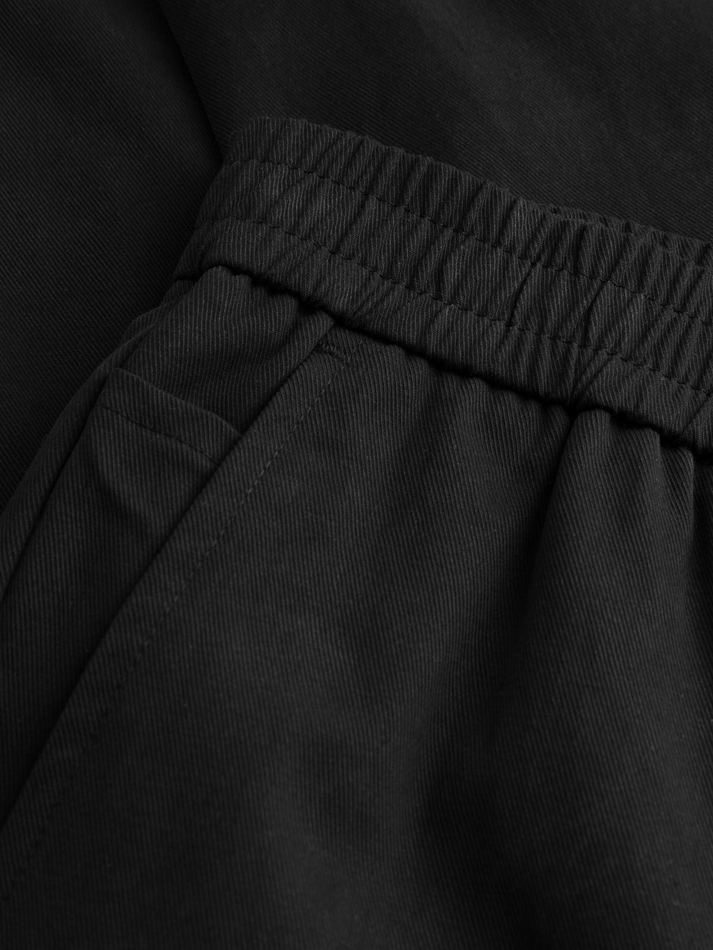 Close-up of Gabba GABmonza Tasca Bolu TENCEL™ Pant in black, featuring a relaxed straight fit, elastic waistband, side pocket, and detailed texture with visible stitching.