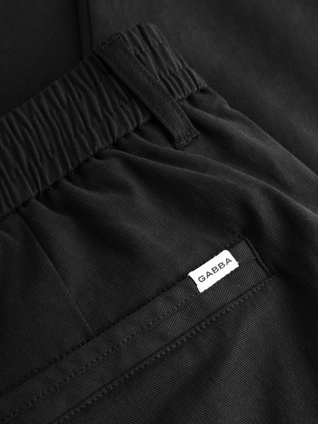 Close-up of the GABmonza Tasca Bolu TENCEL™ Pant in black by Gabba, showcasing an elastic waistband and a white fabric label with 