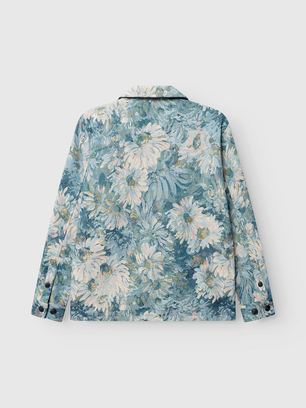 The Gabba GABsimone Art LS - Blue Pattern overshirt features an all-over floral print with large white and pale yellow flowers and green leaves on a light blue background, shown from the back, and has black buttons on the cuffs.