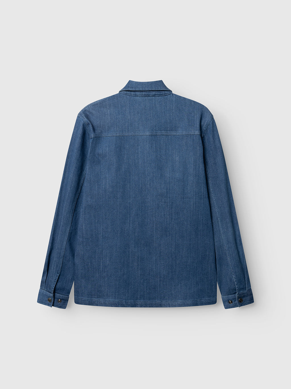 Back view of the Gabba GABbeta Denim LS Overshirt in mid blue denim, featuring long sleeves, a collar, front pockets, buttoned cuffs, and seam details, shown against a light gray background.