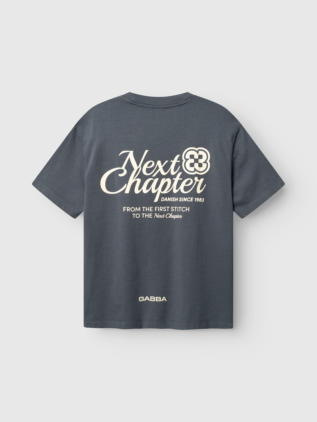 The Gabba GABlegin Wix Chap Boxy Hour SS T-Shirt in Turbulence Blue is a boxy-fit heavyweight cotton tee with a bold graphic back print: “Next Chapter, Danish since 1983. From the first stitch to the Next Chapter.” Gabba logo at hem.
