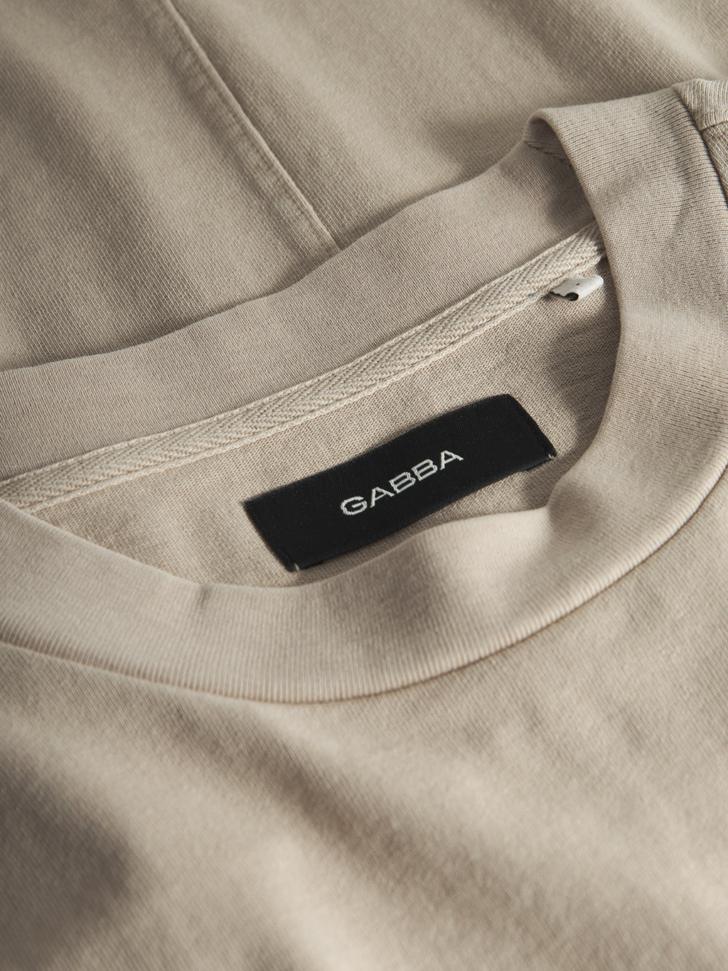 Close-up of the Gabba GABnigel Wix Boxy Hour SS t-shirt in Sand Cashmere, showing its soft heavyweight cotton, detailed stitching, and an inside black Gabba label that highlights the premium boxy construction.
