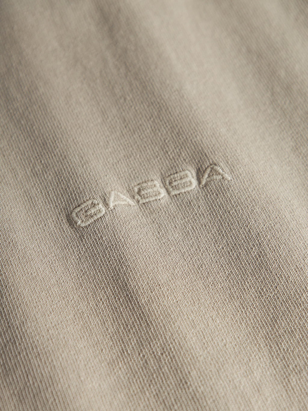Close-up of heavyweight cotton fabric from Gabba’s GABnigel Wix Boxy Hour SS - Sand Cashmere, featuring the word 