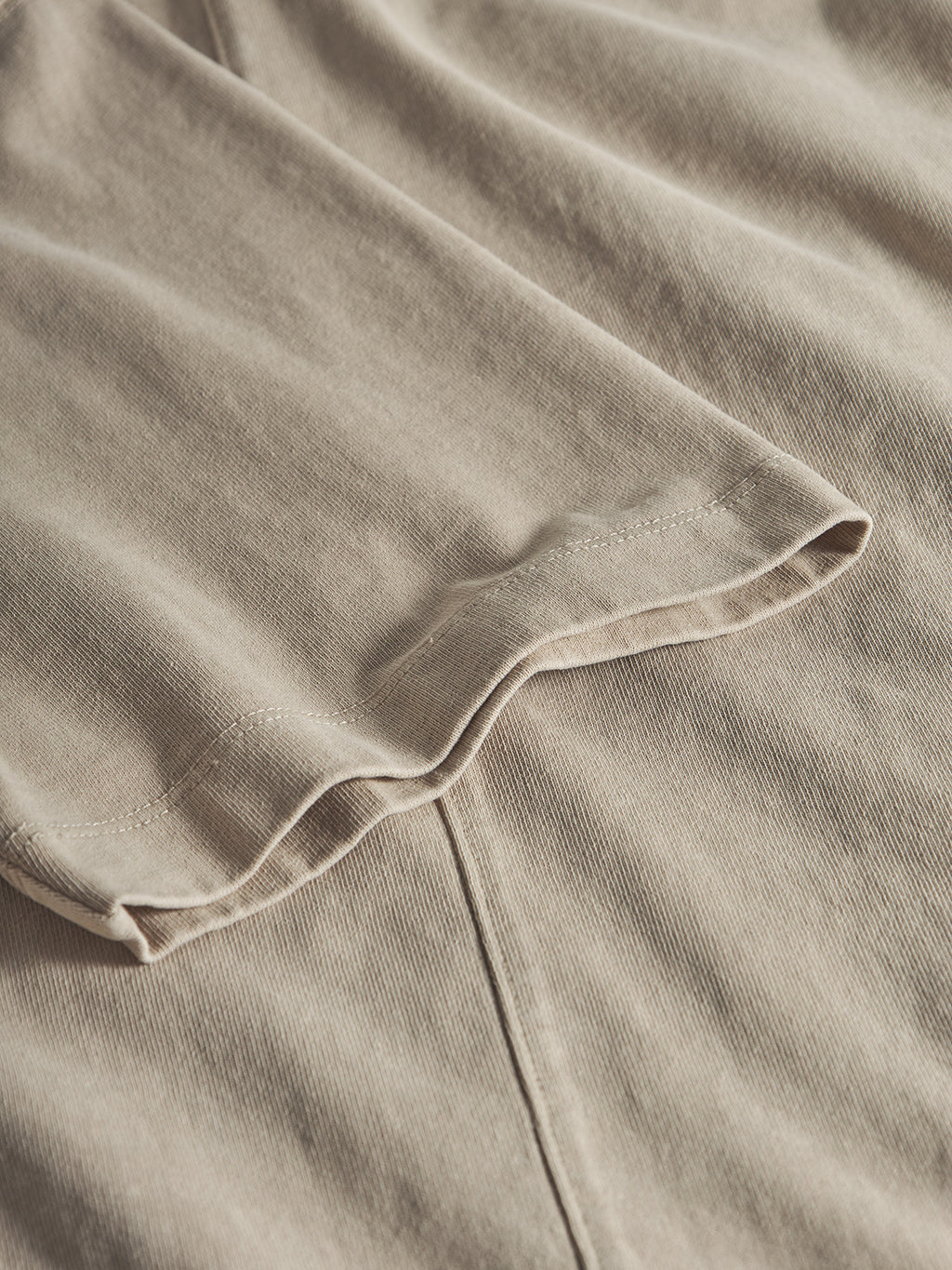 A close-up of the Gabba GABnigel Wix Boxy Hour SS in Sand Cashmere, highlighting its heavyweight cotton fabric and detailed hem and stitching, laid flat.