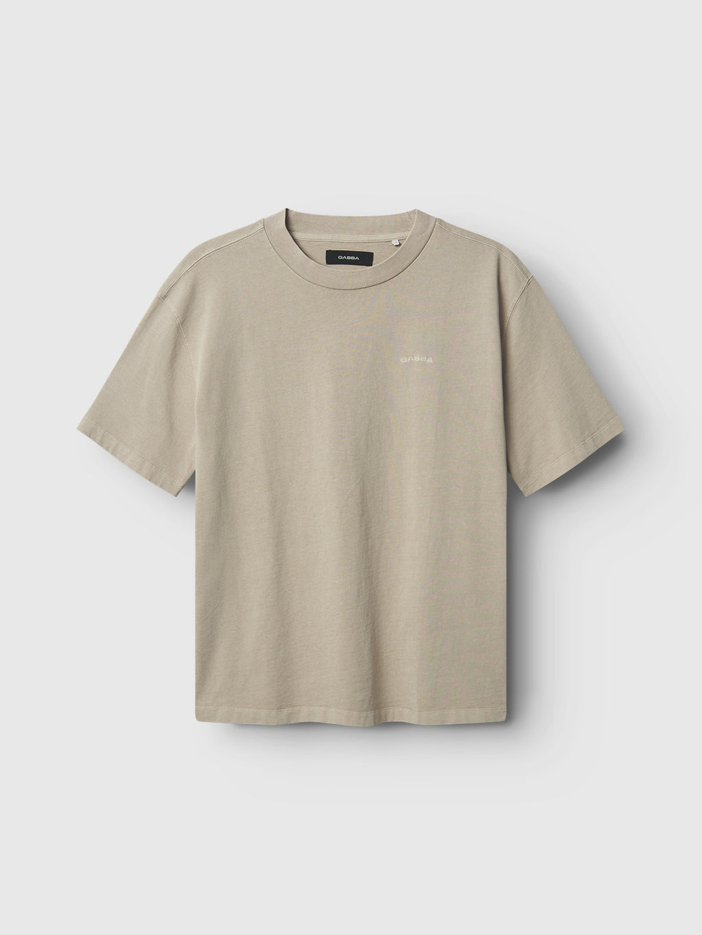The Gabba GABnigel Wix Boxy Hour SS - Sand Cashmere t-shirt, a plain, short-sleeved beige top with a crew neckline and boxy fit, is displayed on a light gray background. Crafted from soft heavyweight cotton, it features a small, subtle logo on the left chest.