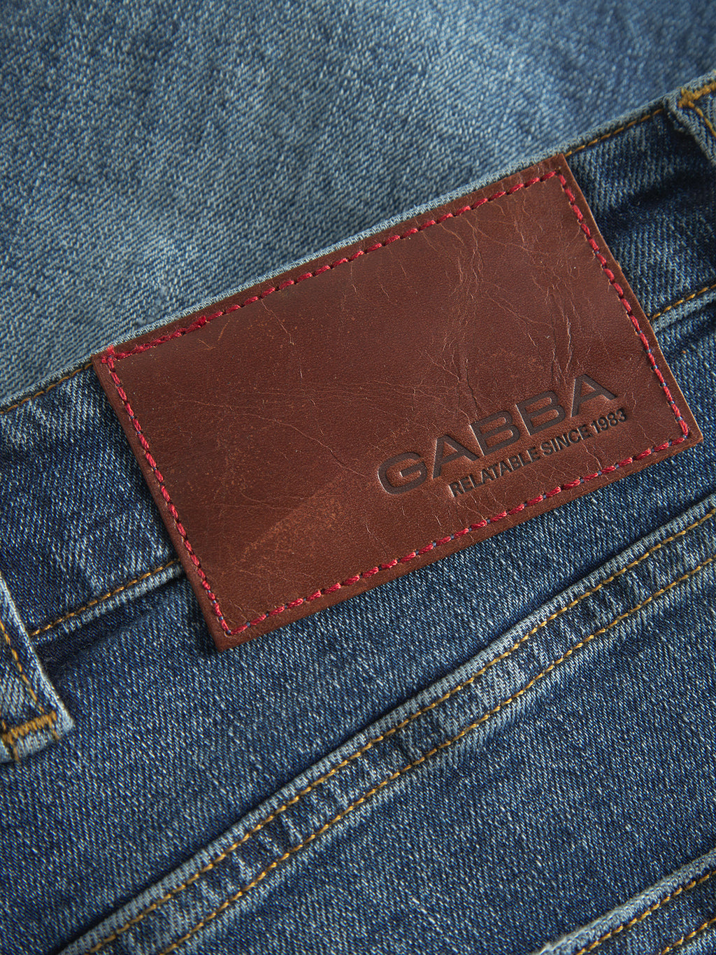 Close-up of GABalex Cros Cropped jeans in mid blue denim by Gabba, made from recycled cotton with a brown leather patch on the waistband embossed 