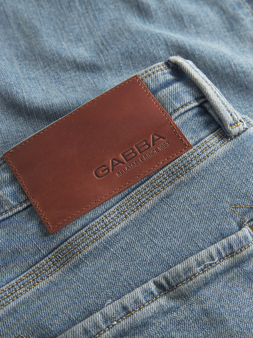 Close-up of GABmax Cros - Lt. Blue Denim jeans by Gabba, featuring an elegant style and a brown leather patch above the back pocket embossed with the brand name and 