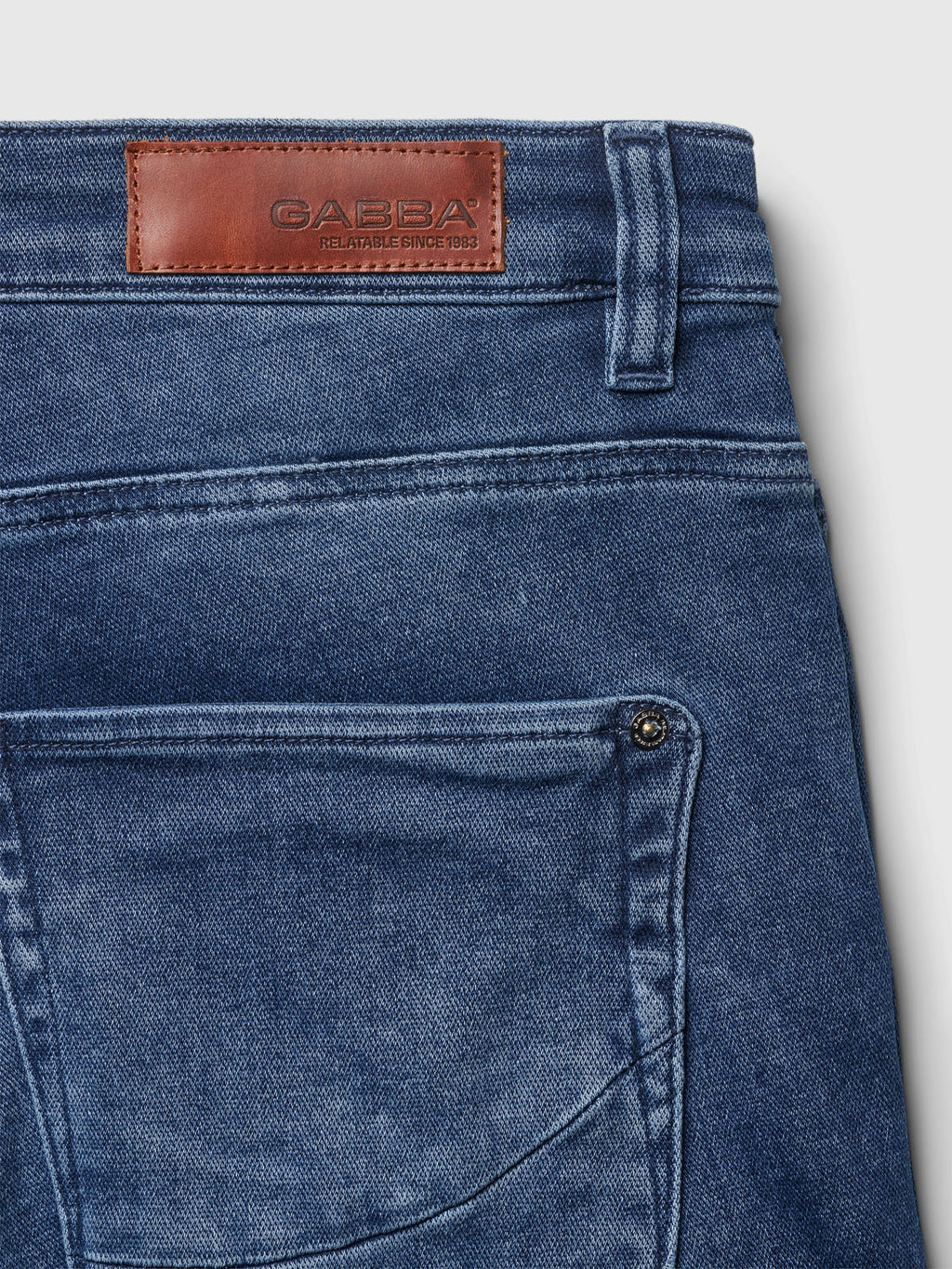 Close-up of the back pocket and waistband of Gabba Jason K3787 SANZA Shorts in mid-blue denim, featuring super-stretch fabric and a brown leather patch reading 