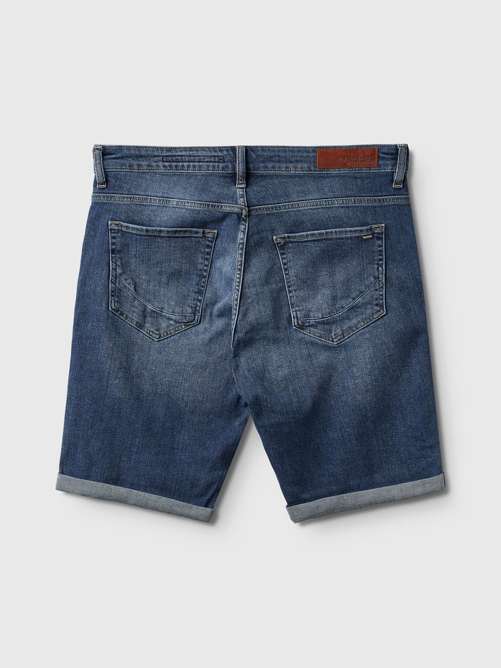 Back view of Gabba Markus K4664 Shorts in mid blue denim, made from recycled cotton with rolled hems, two back pockets, and a brown leather waistband patch, shown against a plain light background.