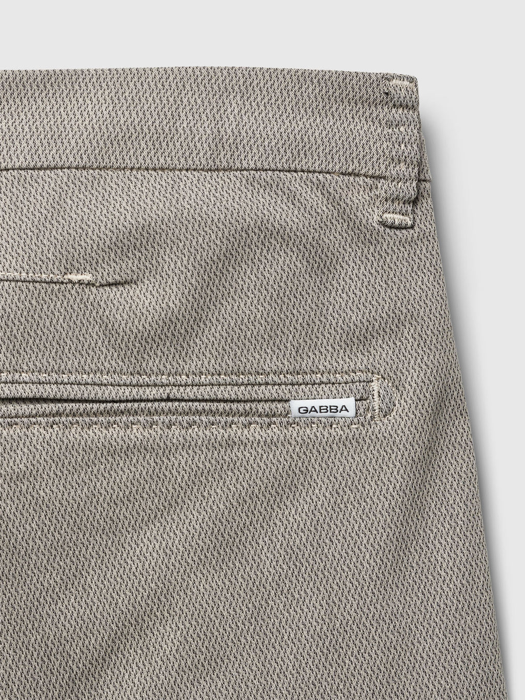 Close-up of the back pocket area of Gabba's GABjet K3280 Dale Shorts in Birch, a light gray textured, versatile design featuring a zipper pocket with a small white Gabba tag sewn beside the zipper.