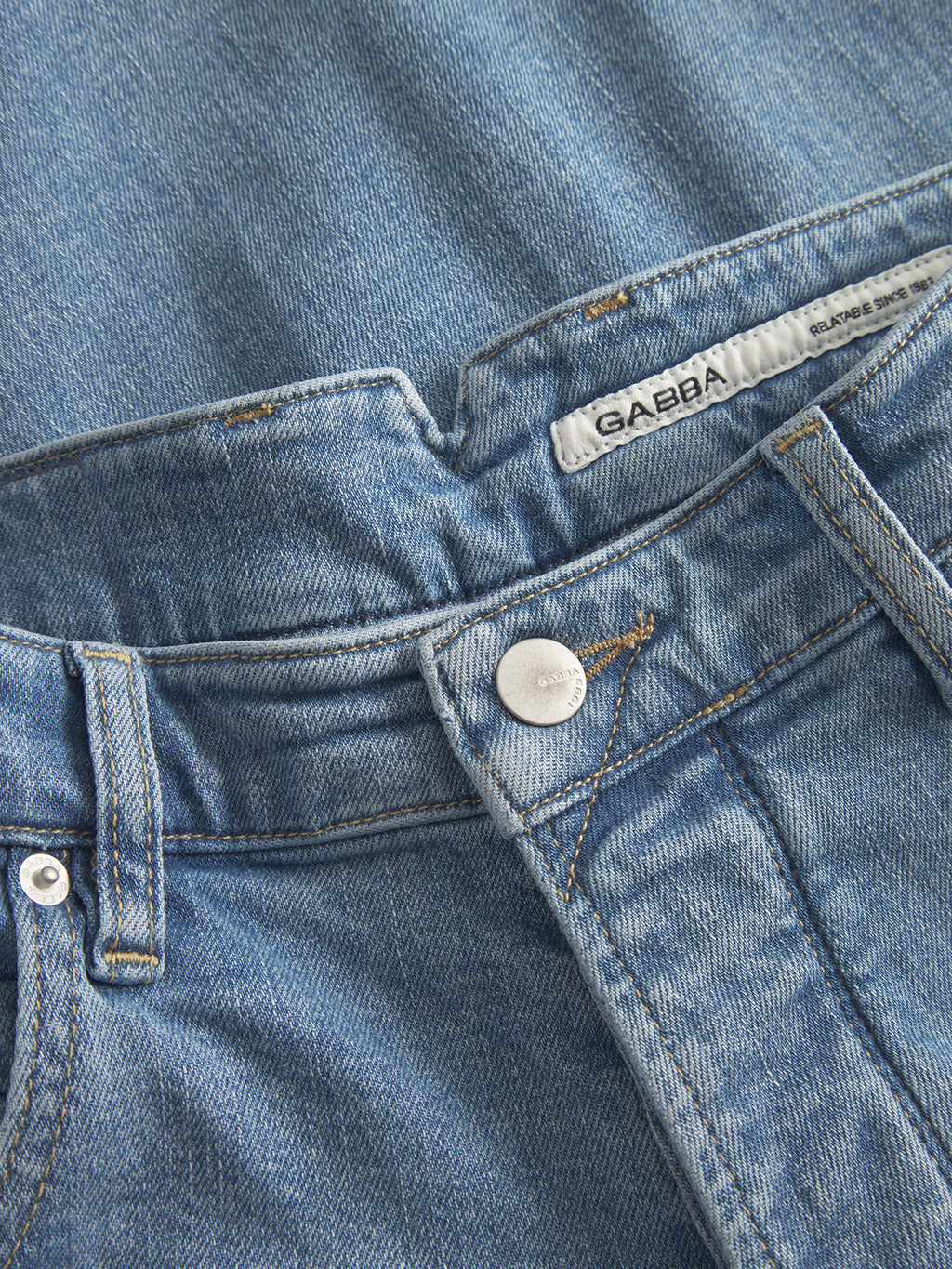 Close-up of Gabba GABalex Cross light blue denim jeans, showing a metal button, belt loops, stitching details, and an inner white label stating 