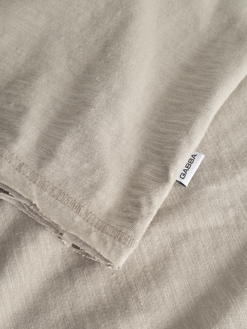 Close-up of the GABkostant New SS t-shirt in Grey Paloma by Gabba, featuring soft, textured slub fabric and detailed stitching. A small white tag shows the brand name Gabba in black text.