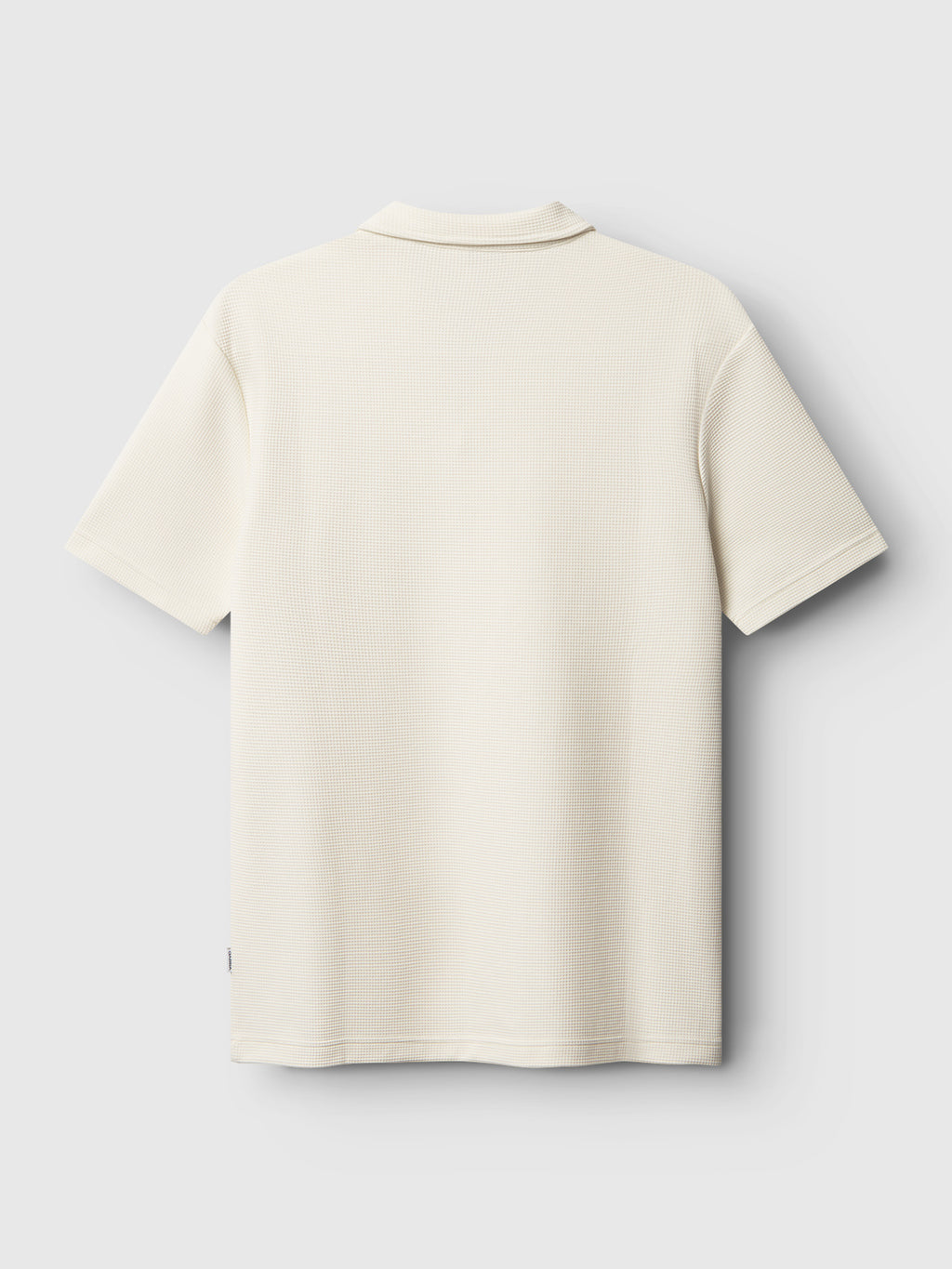 The Gabba GABlio Waff polo in Bone White, made from midweight waffle fabric, is shown from the back against a light gray background. This short-sleeve shirt features a simple collar and subtle textured finish.