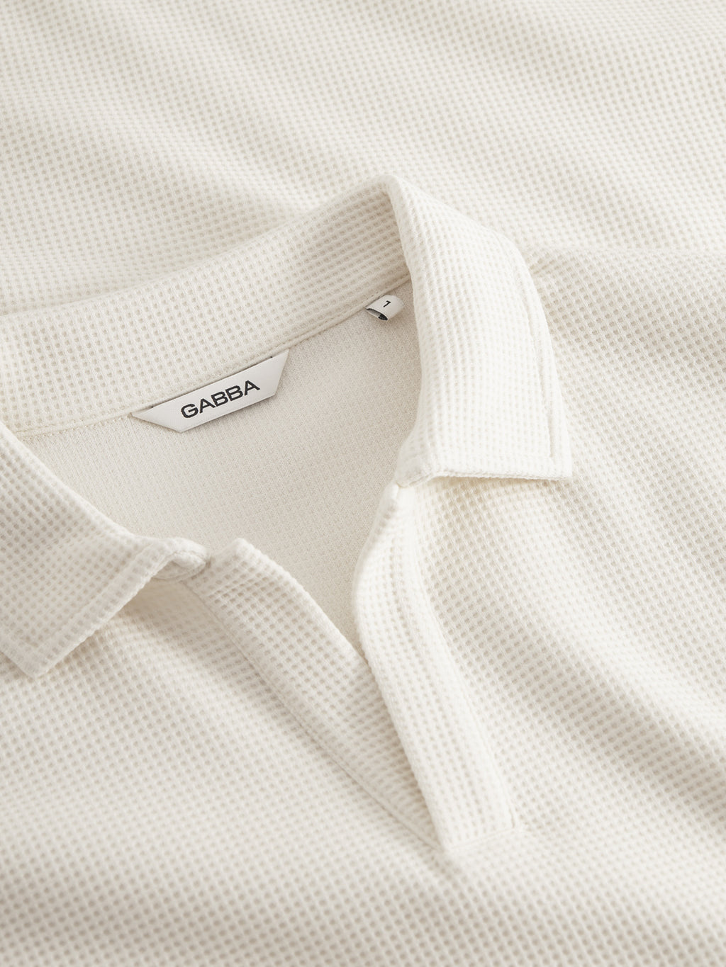 Close-up of the Gabba GABlio Waff polo in Bone White, showcasing its midweight waffle texture, open collar, partial placket, and a visible Gabba tag.