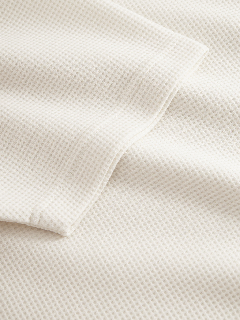 A close-up of the Gabba GABlio Waff in Bone White reveals its midweight waffle fabric and small honeycomb pattern—gentle folds make it ideal for showcasing a Gabba embroidery logo or complementing an open collar design.