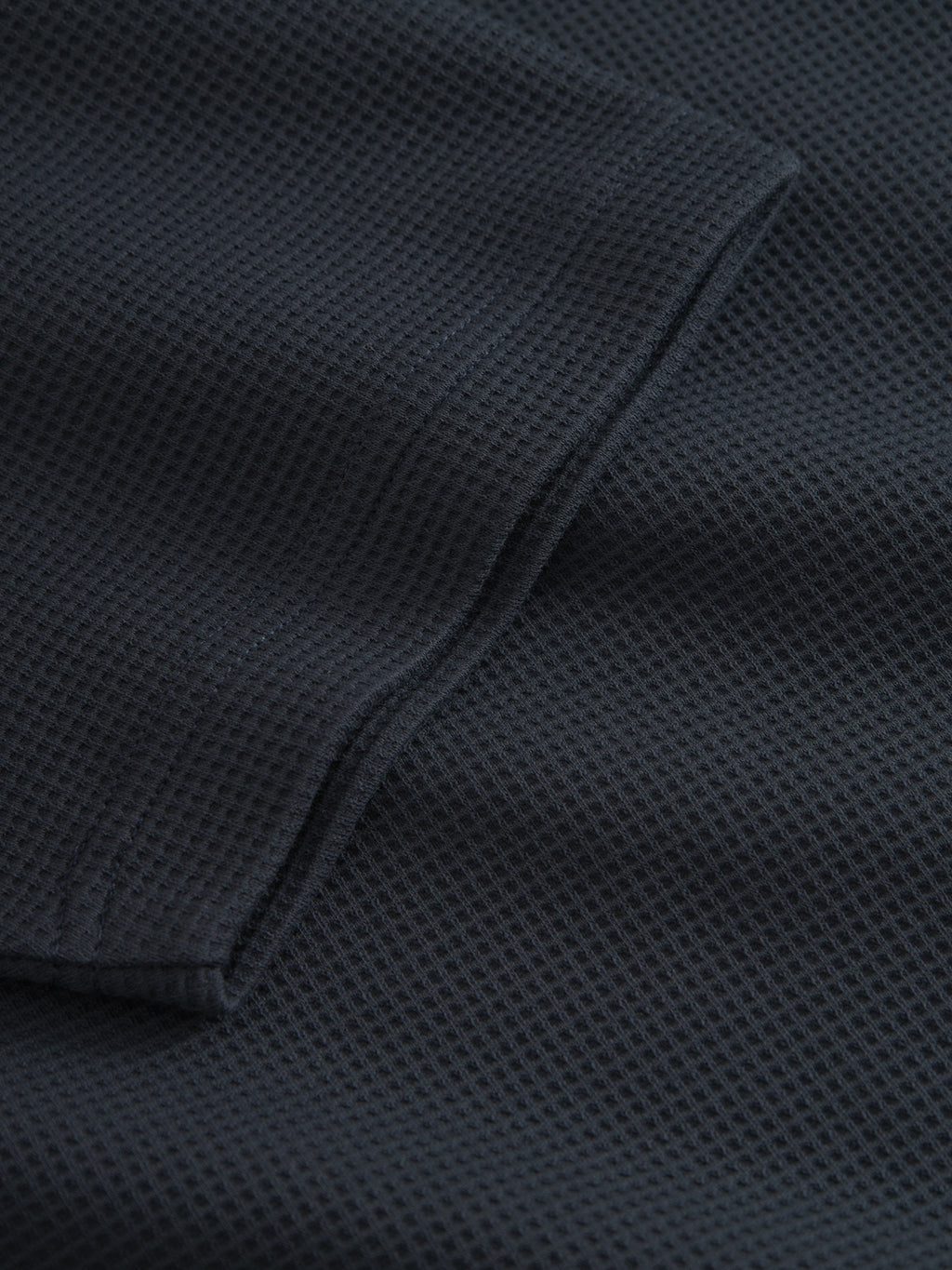 Close-up of the GABlio Waff - Navy's dark, midweight waffle fabric by Gabba. The grid-like texture and folded edge highlight neat stitching and subtle Gabba embroidery.