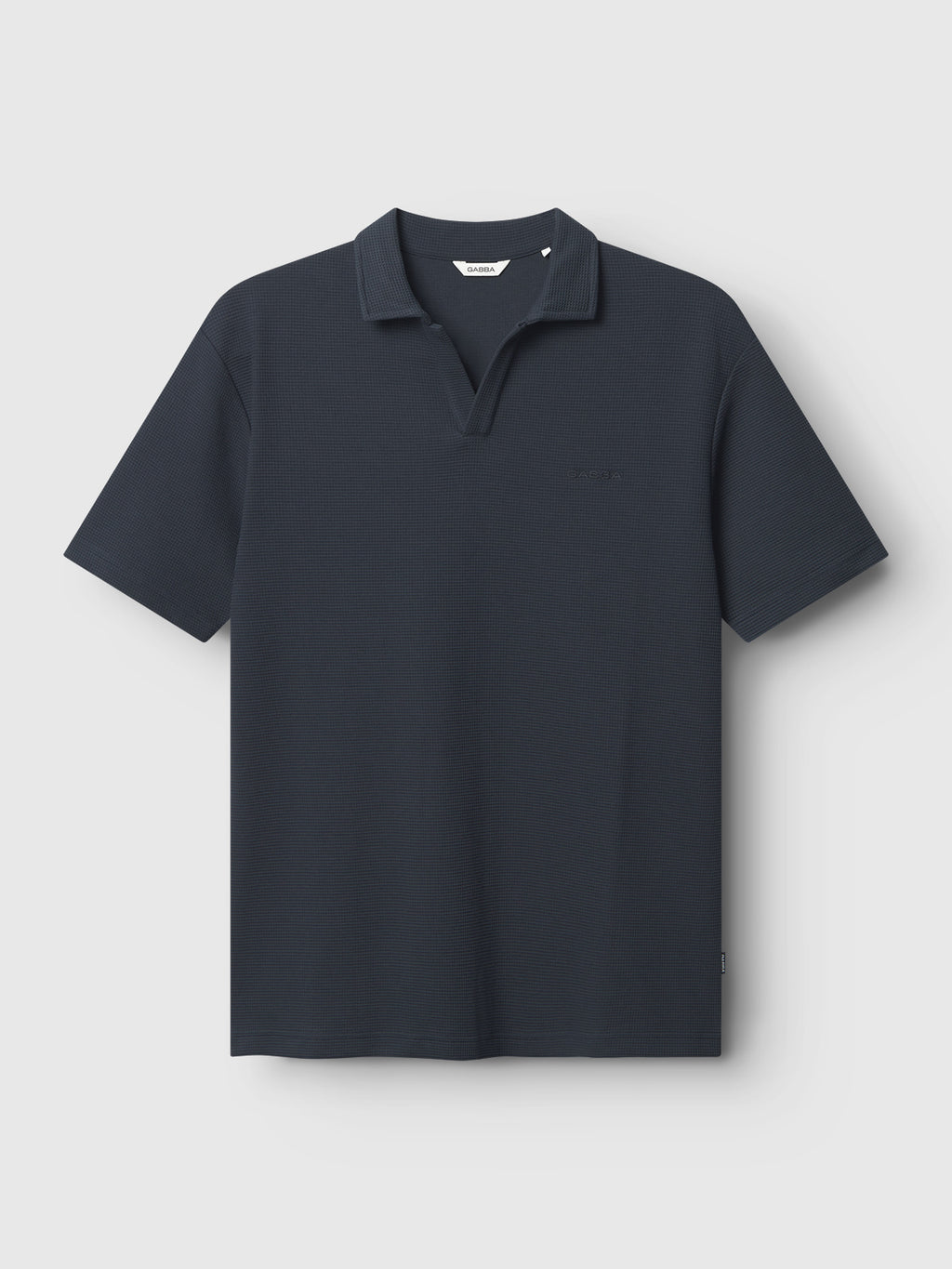 Gabba's GABlio Waff in Navy is a short-sleeved polo shirt with an open collar, made from midweight waffle fabric and featuring subtle Gabba embroidery on the left chest, shown laid flat on a white background.