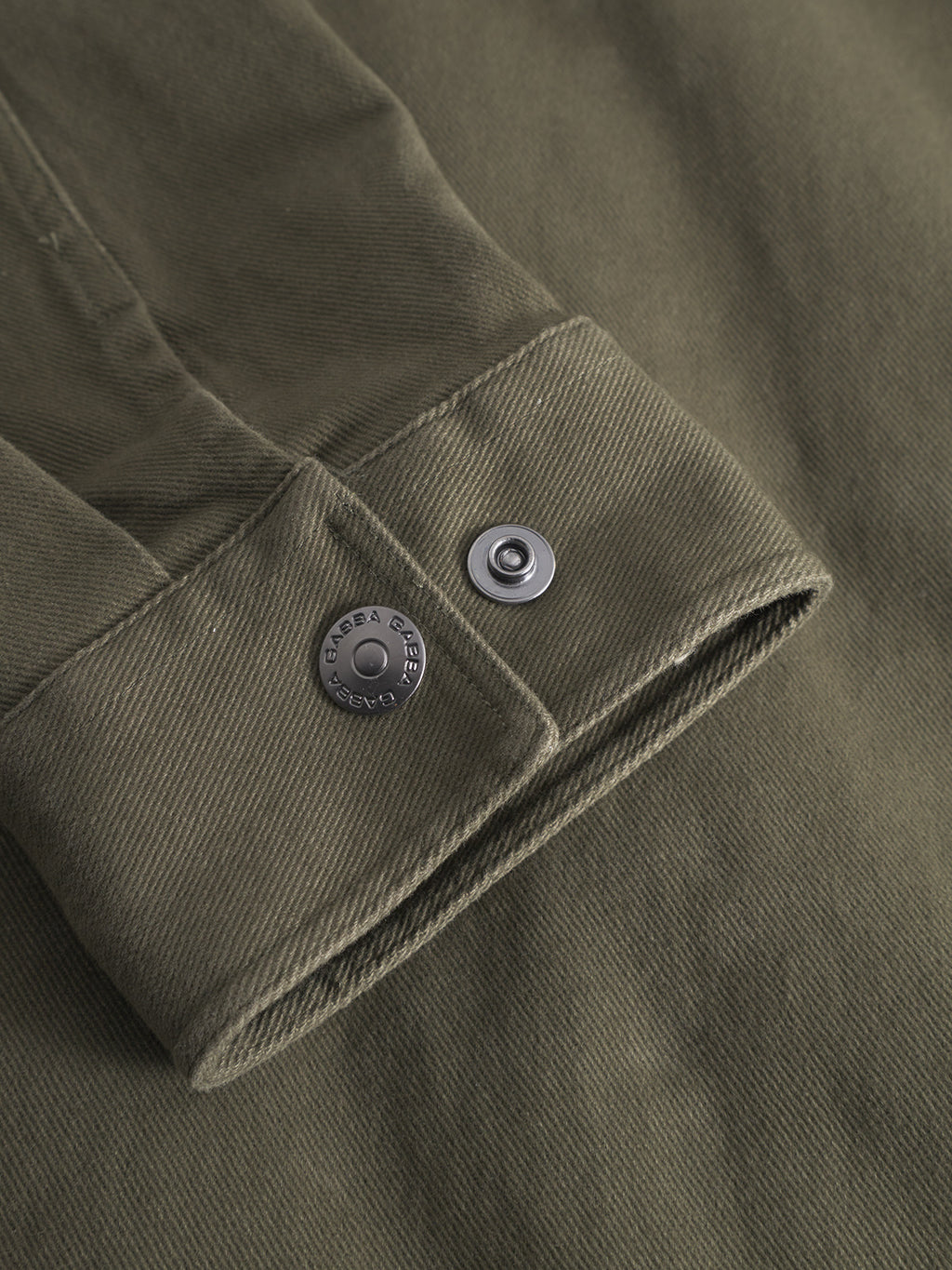 Close-up of the GABbeta Twill - Army overshirt by Gabba, featuring olive green cotton twill, detailed stitching, and two metal snap buttons—one engraved and one plain—highlighting classic workwear style.