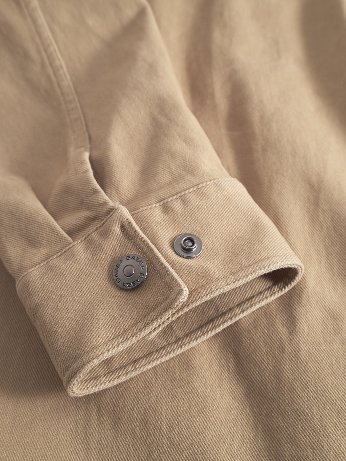 Close-up of the Gabba GABbeta Twill – Sand overshirt’s beige denim sleeve, highlighting its metal snap button, garment-dyed twill texture, and detailed seams.