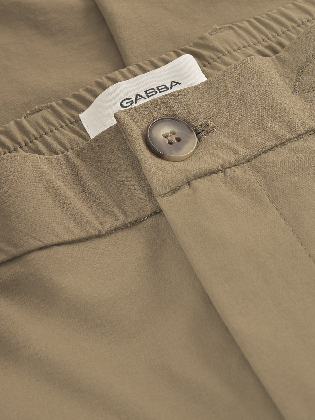 Close-up of GABmonza Tech - Army pants by Gabba, featuring a relaxed straight fit, elastic waistband, brown button, and visible white Gabba label in black letters.