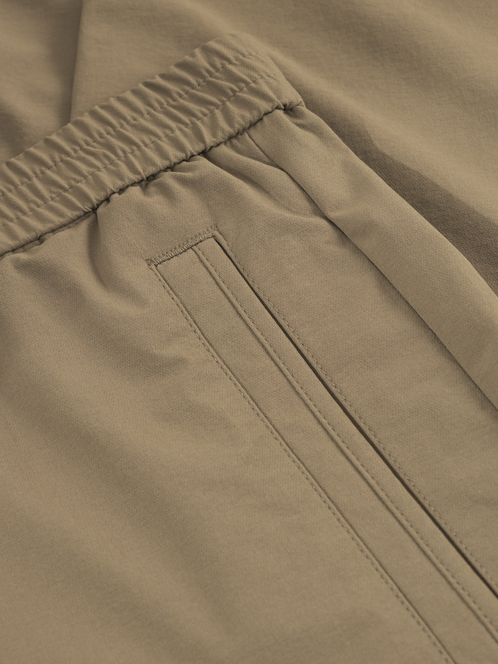 Close-up of Gabba’s GABmonza Tech - Army pants in light brown, featuring an elastic waistband, durable tech fabric, and a neatly stitched horizontal slit pocket.