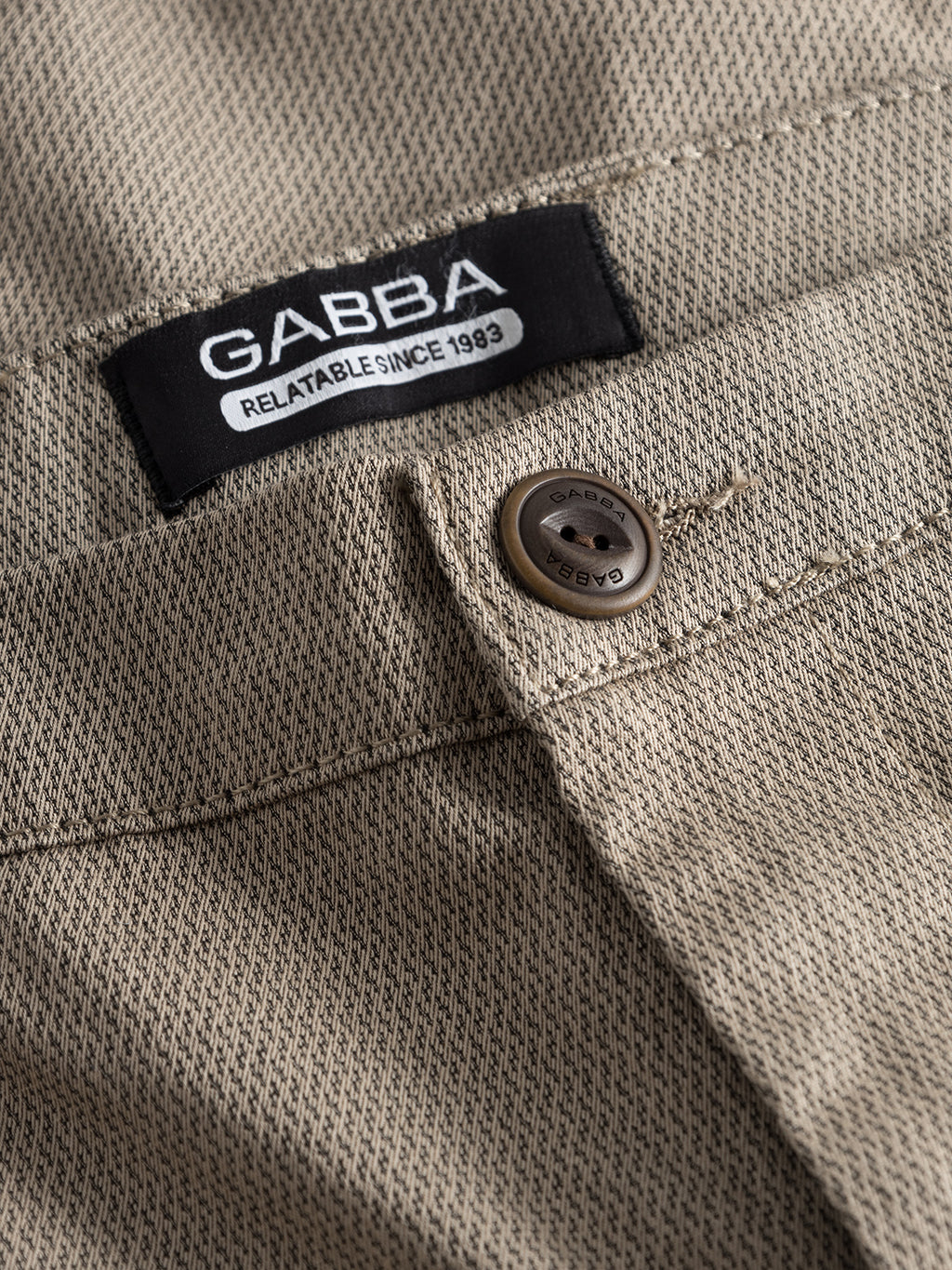 Close-up of beige GABBA Pisa K3280 Dale Pants - Humus with a textured tapered fit, a visible black GABBA label reading 
