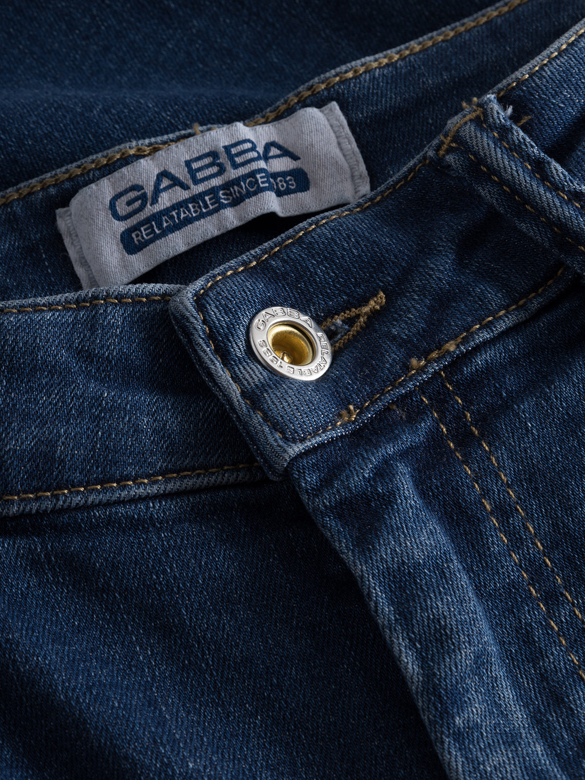 Close-up of Gabba GABjones K3870 slim jeans in mid blue denim, featuring a metal button, detailed stitching, and a fabric label reading 
