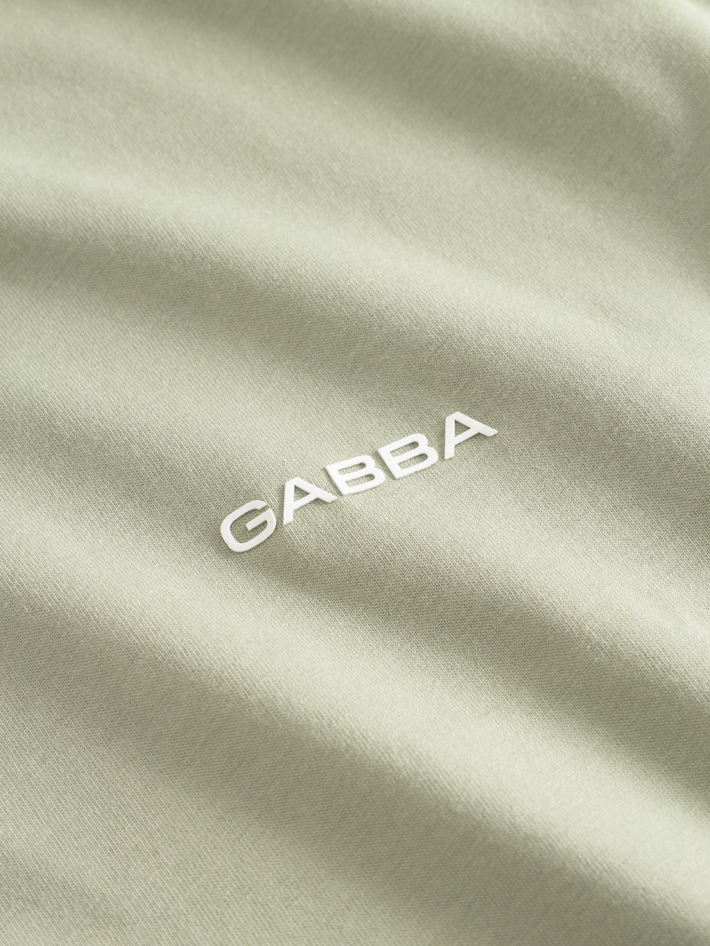 A close-up of the Gabba GABdune Logo GOTS SS T-Shirt in light green shows its smooth organic cotton fabric and bold, white “GABBA” logo at the center, highlighting this classic fit tee’s premium look and feel.