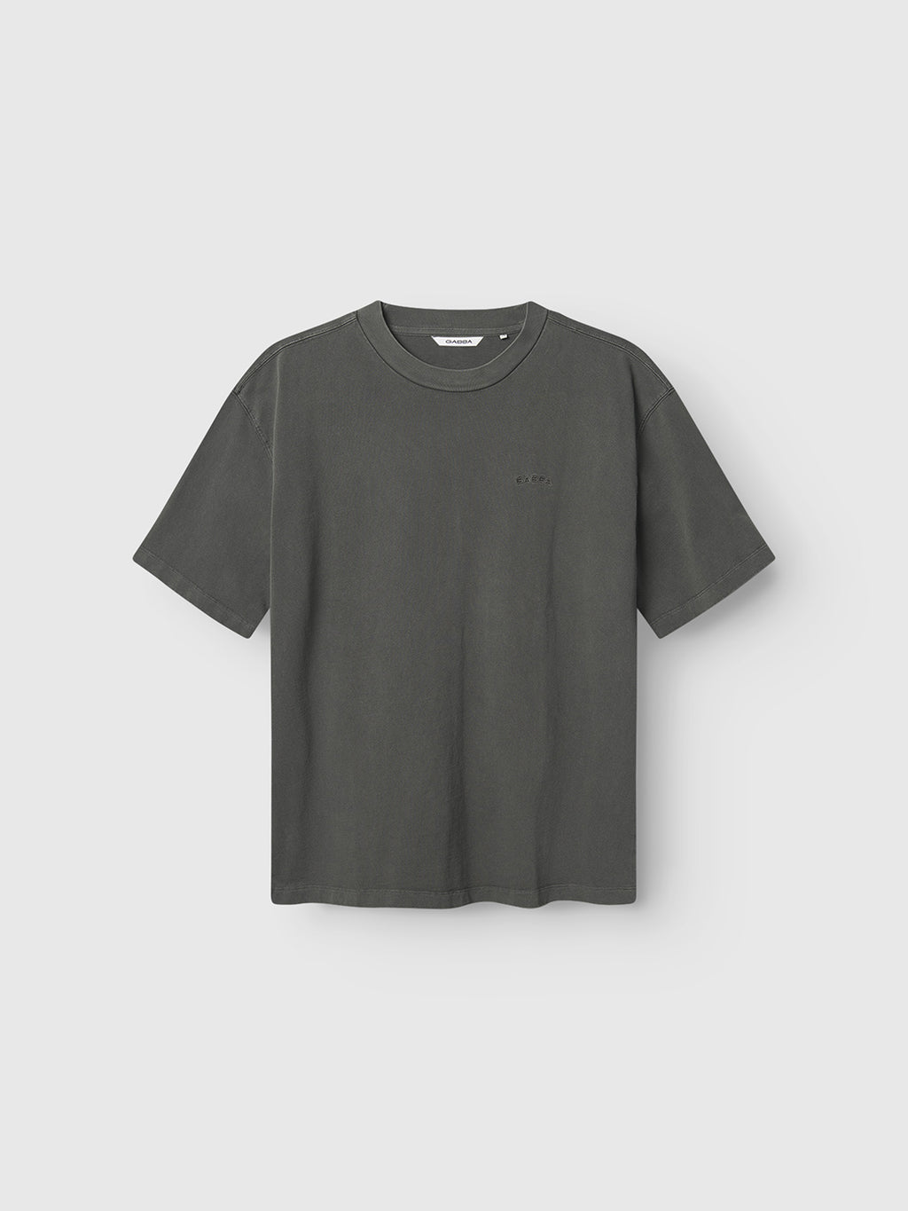 The Gabba GABnigel Wix Boxy Hour SS in dark grey is a heavyweight cotton t-shirt with a relaxed, boxy fit and crew neckline, shown on a light gray background. Minimal detailing gives it a clean, modern look.