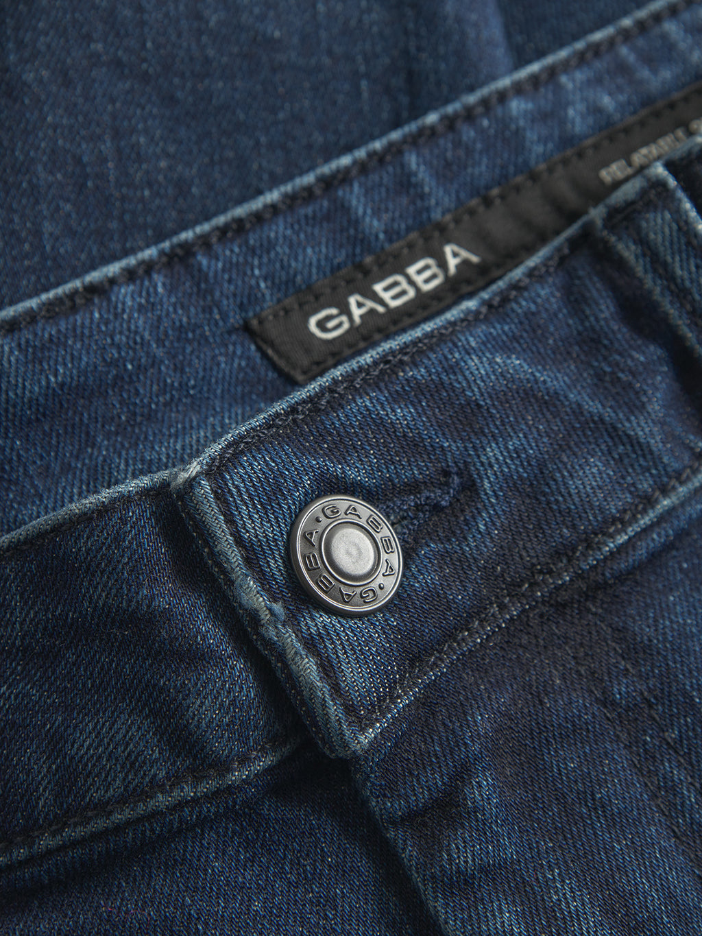 Close-up of GABmarc Mego - Dark Blue Denim jeans featuring a metal button engraved with Gabba and a black label with the Gabba brand name sewn into the waistband.