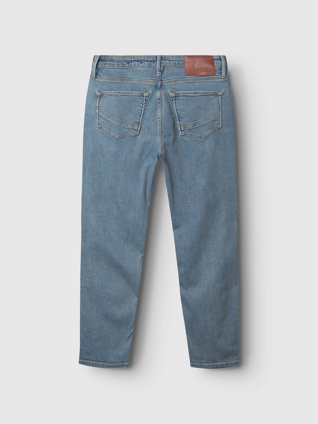 The Gabba GABmax Cros - Lt. Blue Denim jeans feature two back pockets, belt loops, and a brown leather patch on the waistband, offering a sharp, clean look with a modern slim fit.