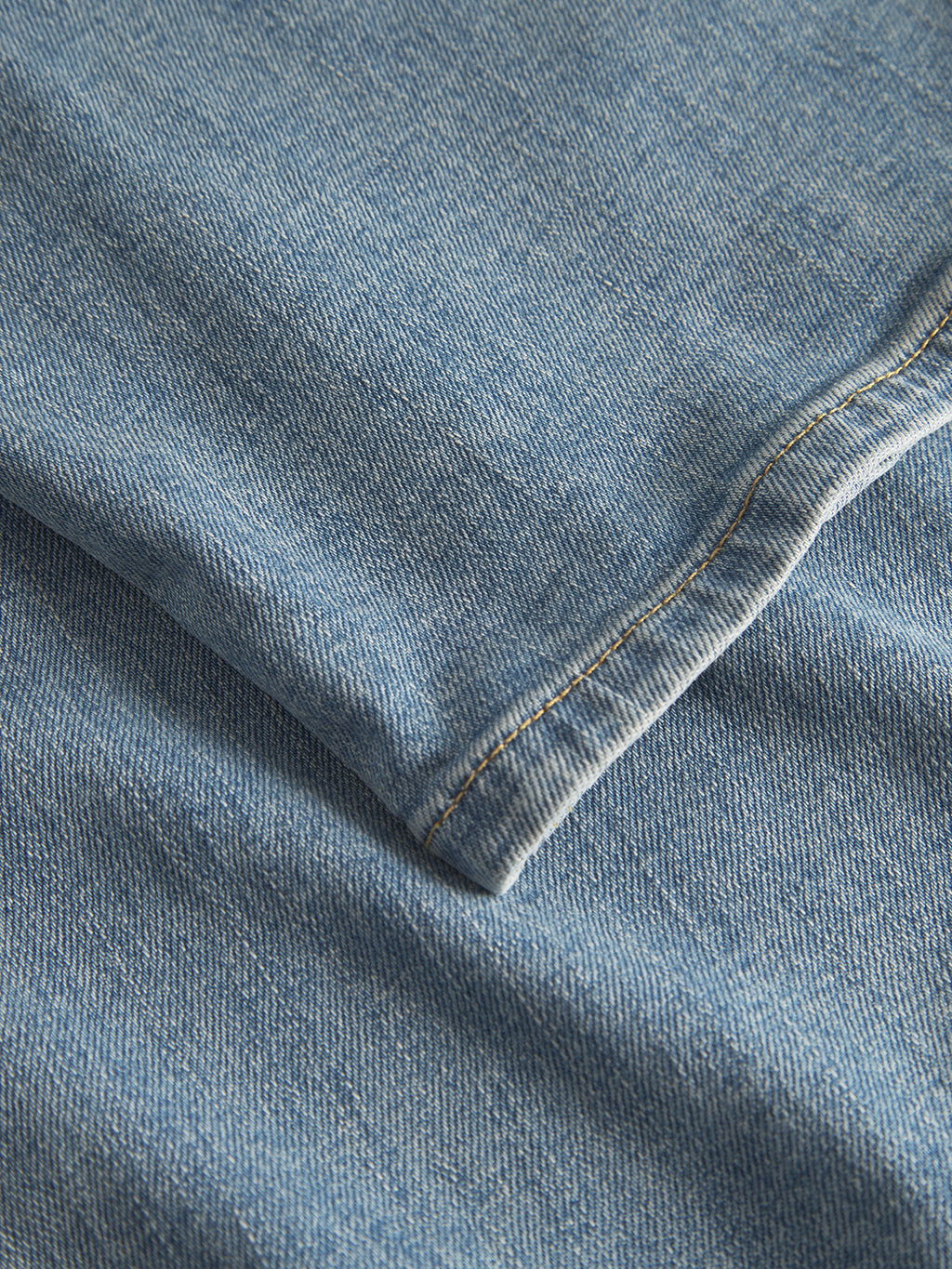 Close-up of Gabba’s GABmax Cros in Lt. Blue Denim, showing modern slim fit fabric with a folded edge, visible brown stitching, and textured weave.