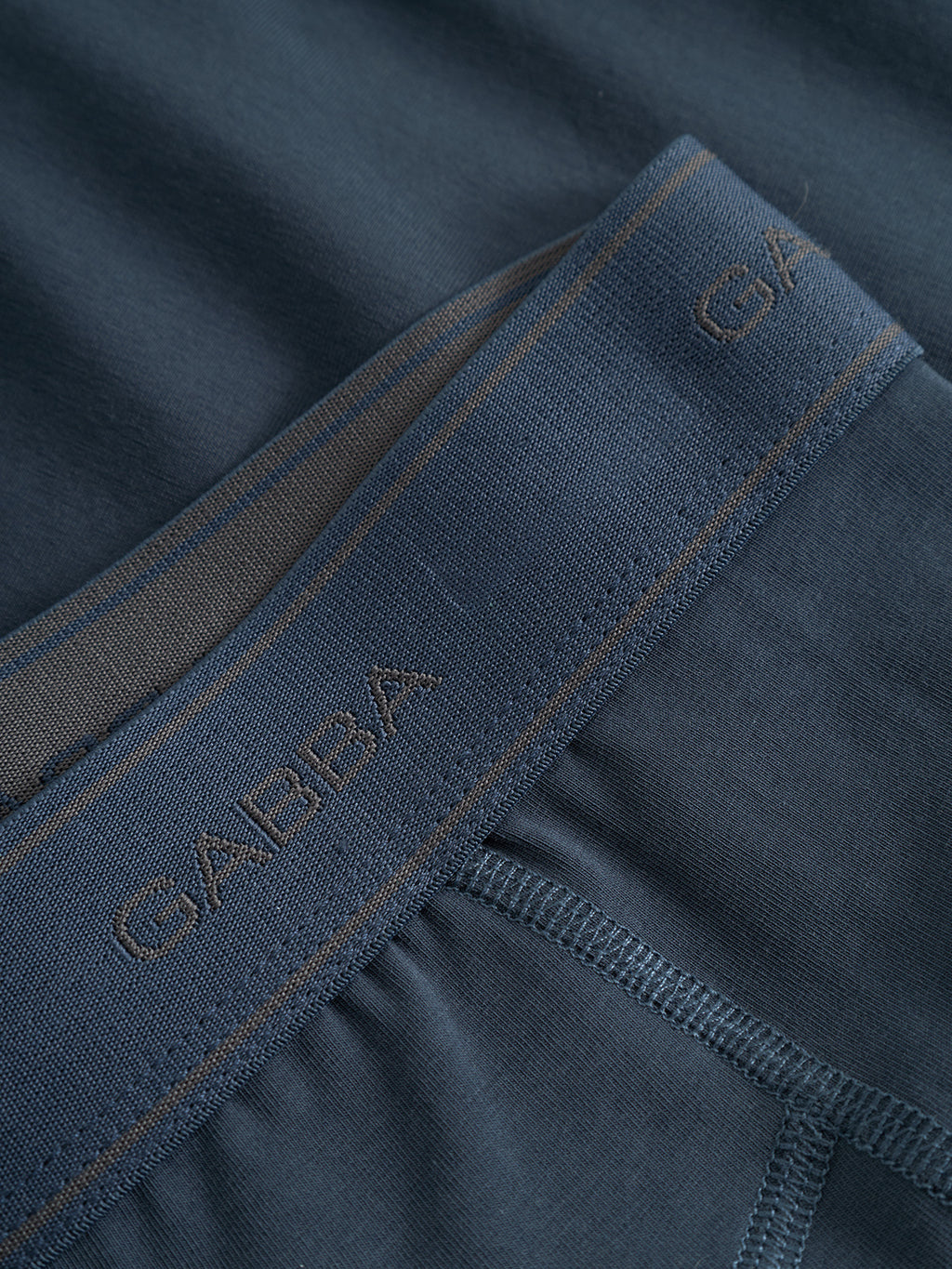 Close-up of Gabba's Trunk New - Black Iris: men's soft cotton trunks in navy blue with fine stitching, a smooth fabric texture, and the Gabba logo on the waistband.