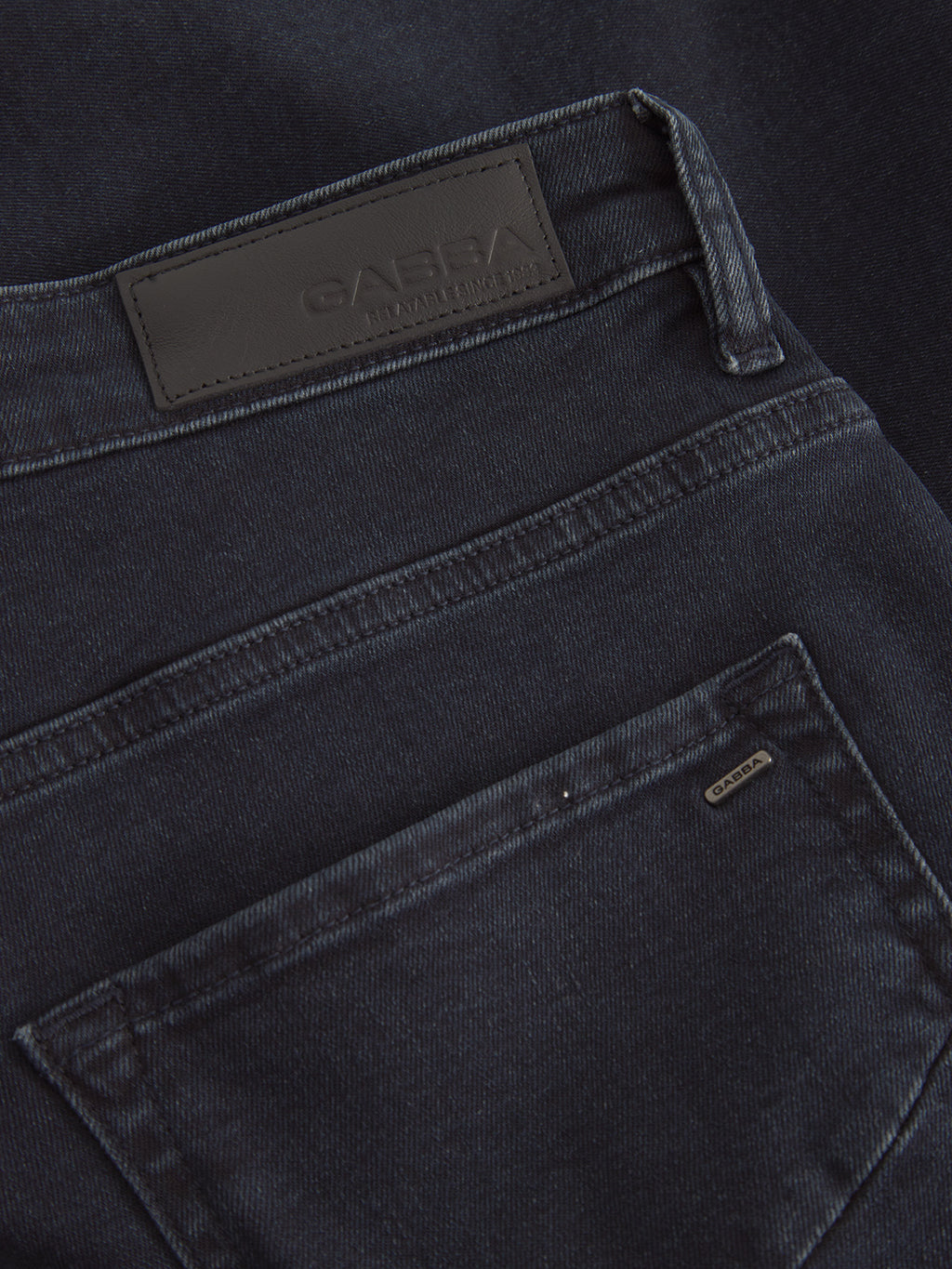 Close-up of the back pockets of GABmarc Panter dark blue denim straight fit jeans by Gabba, featuring a black leather patch with embossed Gabba branding and a small metallic tag on the upper right pocket edge.